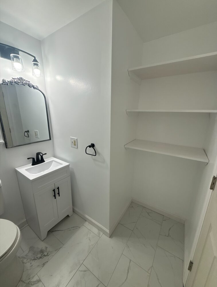 The same bathroom after Eclipse: clean white walls with a new vanity and built-in shelving