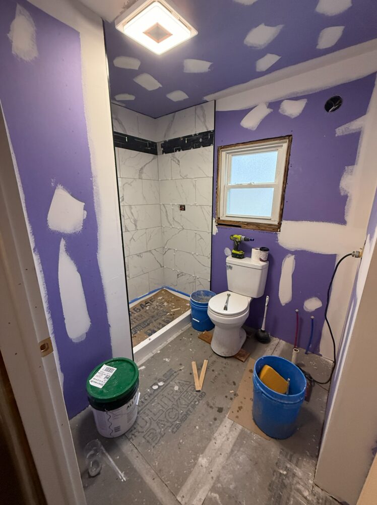 Bathroom before painting: unfinished walls around a newly tiled shower