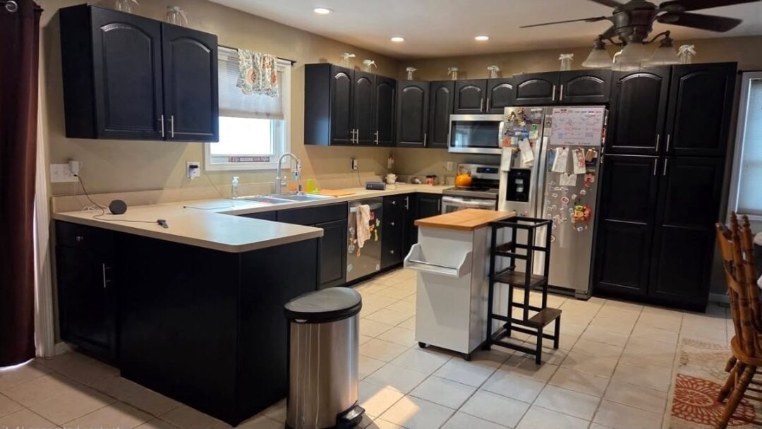 The same kitchen after Eclipse: every cabinet painted a deep satin black with new pulls, counters and floor untouched
