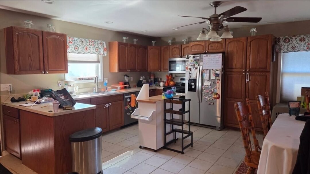 Kitchen before: dated orange-toned oak cabinets throughout, with a light laminate counter and tile floor